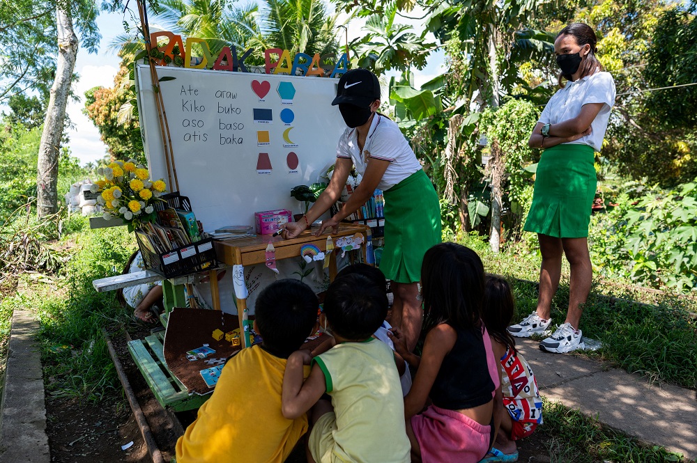 A student volunteer teaches children through their makeshift trolley which serves as a mobile library, near the railroad, in Tagkawayan, Quezon Province, Philippines February 15, 2022. — Reuters pic