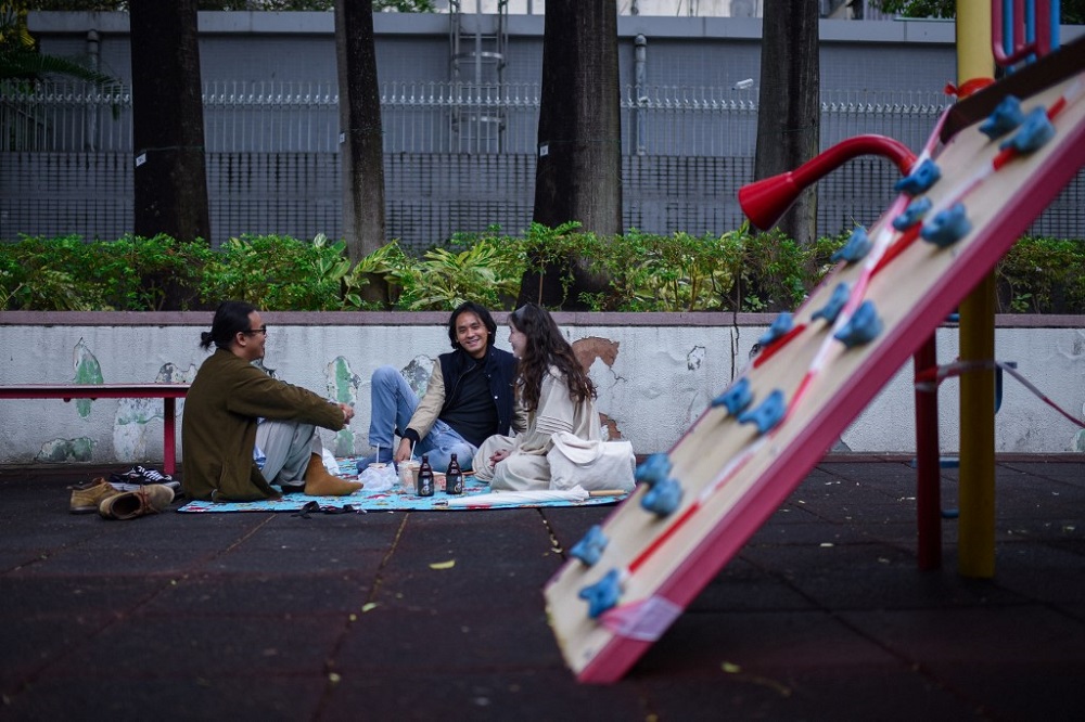 Dominic (left), Bu (centre) and Birdy (right), creators of a social media picnicking group, having a picnic in a public seating area next to a play area for children (right), closed due to Covid-19 restrictions, in Hong Kong January 22, 2022. u00e2u20acu201d AFP pic 