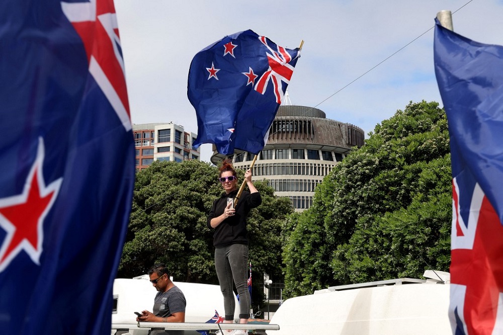 Protesters wave flags from vehicles parked on the streets outside the parliament building (behind) during a demonstration against Covid restrictions in Wellington February 8, 2022. u00e2u20acu201d AFP pic