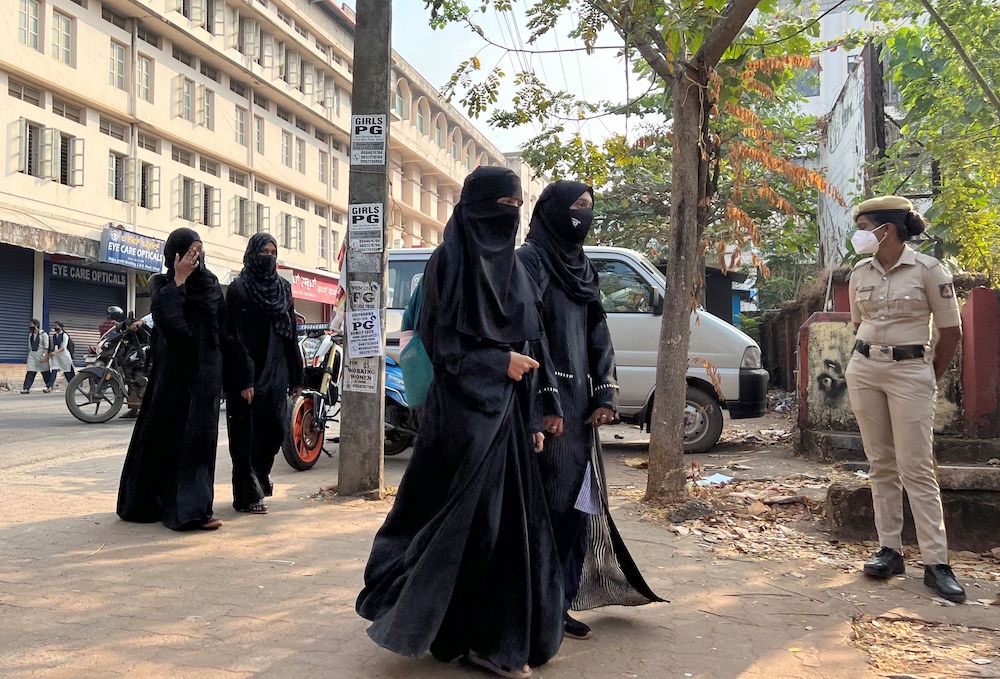 Hijab wearing schoolgirls arrive to attend their classes as a policewoman stands guard outside a government girls school after the recent hijab ban, in Udupi town in the southern state of Karnataka, India, February 16, 2022. u00e2u20acu201d Reuters picnn