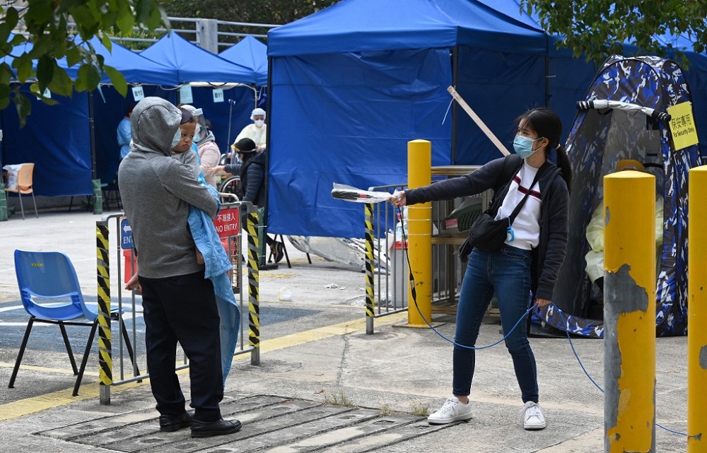 A journalist (right) keeps her distance as she interviews a father and son at a temporary centre for patients set up outside the Caritas Medical Centre in Hong Kong February 16, 2022. u00e2u20acu201d AFP pic