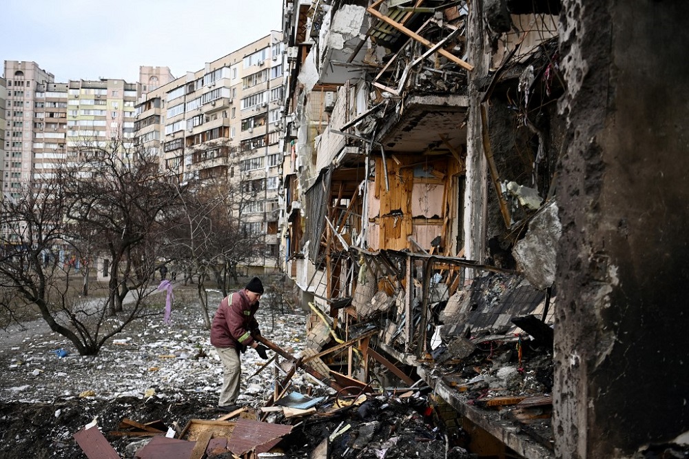 A man clears debris at a damaged residential building where a military shell allegedly hit at Koshytsa Street, a suburb of the Ukrainian capital Kyiv February 25, 2022. u00e2u20acu201d AFP pic