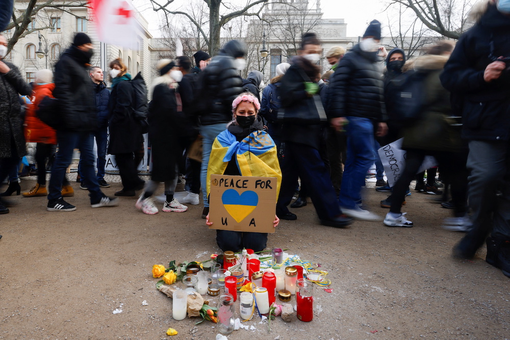A person reacts as she prays in front of the Russian Embassy as demonstrators walk by during an anti-war protest, after Russia launched a massive military operation against Ukraine, in Berlin, Germany, February 27, 2022. u00e2u20acu201d Reuters picnn