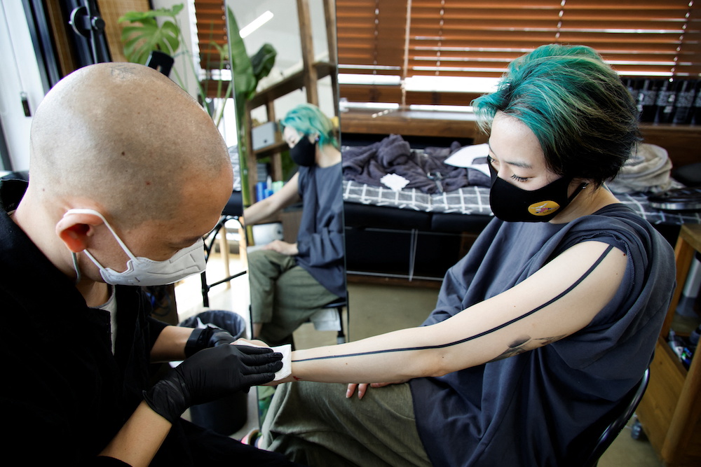 Tattooist Kim Do-yoon attends to a customer in his tattoo studio in Seoul, South Korea February 15, 2022. u00e2u20acu201d Reuters pic