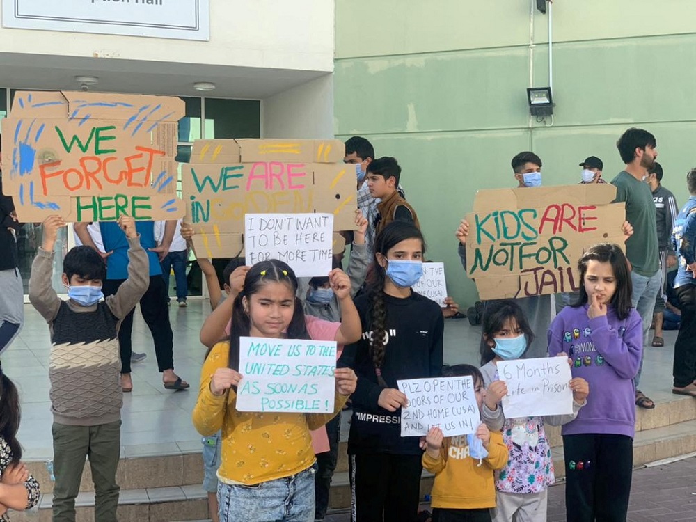 Afghan children hold banners during a protest at a Gulf facility where they have been housed since fleeing their homeland last year, in Abu Dhabi, United Arab Emirates February 10, 2022. u00e2u20acu2022 Rise to Peace/via Reuters