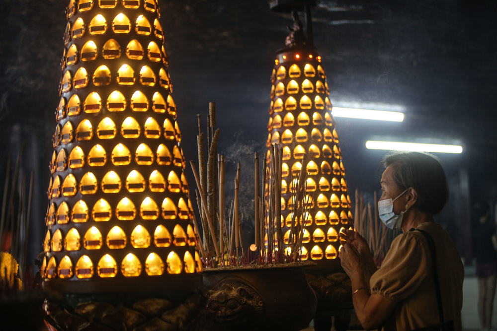 A woman performs prayers during the Chinese New Year celebration at Ling Sen Tong Temple in Ipoh. — Picture by Farhan Najib