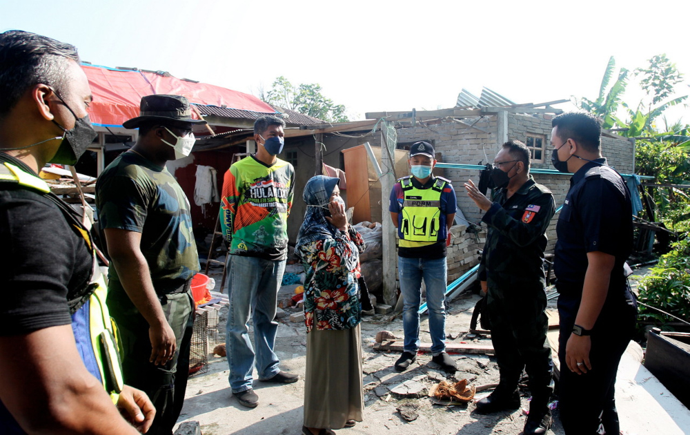 GOF assistant commanding officer DSP Mazian Jenal (2nd right) talks to a resident Azmi Mohd Rashid during the cleanup operation at Taman Desa Sri Chepor in Perak, February 2, 2022. u00e2u20acu201d Bernama pic     