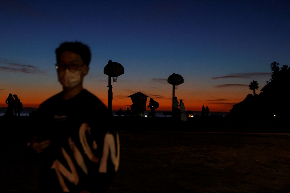 A man wearing a protective face mask walks during sunset in Laguna Beach, California January 24, 2022. u00e2u20acu2022 Reuters file pic
