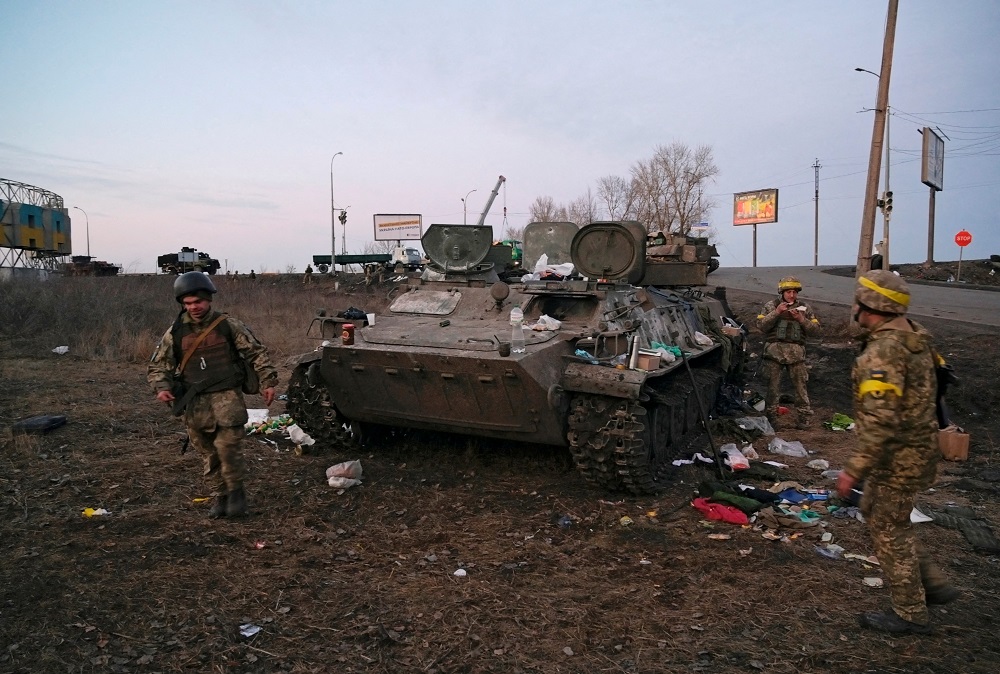 Ukrainian servicemen are seen next to a destroyed armoured vehicle, which they said belongs to the Russian army, outside Kharkiv, Ukraine February 24, 2022. u00e2u20acu2022 Reuters pic