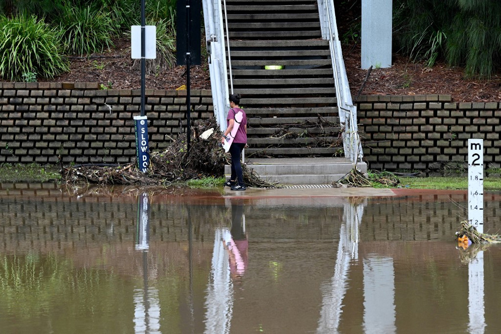 A woman makes her way next to spillover from the flooded Parramatta river at the ferry wharf in Sydney on February 23, 2022, after heavy rain lashed eastern Australia. u00e2u20acu201d AFP pic