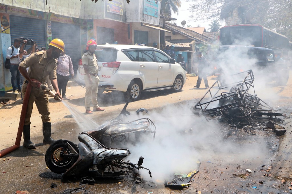 In this picture taken on February 21, 2022, a fireman douses fire from a burning vehicle set on fire by a mob after an unrest followed by the killing of a member of the Hindu nationalist group Bajrang Dal in Shivamogga. u00e2u20acu201d AFP pic 