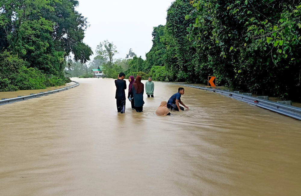 Residents wade through floodwaters at Kampung Bukit Kecik, Bendang Nyior on a road leading to Tanah Merah February 27, 2022. u00e2u20acu201d Bernama pic