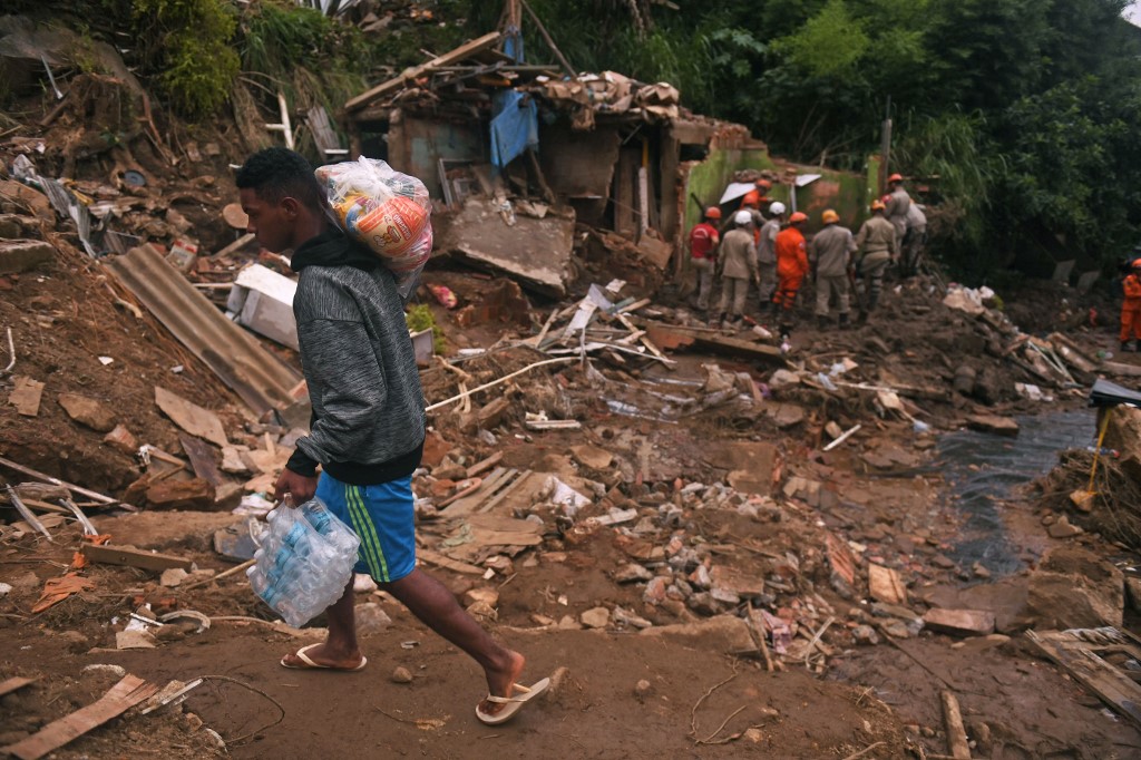 A man holds donations as he passes by the zone of a giant landslide at Caxambu neighbourhood in Petropolis, Brazil, on February 19, 2022. A total of 136 bodies have been retrieved to date, according to civil defence officials. u00e2u20acu201d AFP pic