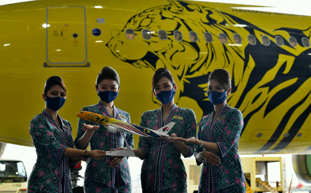 Malaysia Airlinesu00e2u20acu2122 cabin crew poses with a replica of the plane in front of the Airbus A330-300 aircraft with special livery bearing the Harimau Malaya emblem in Sepang, February 8, 2022. u00e2u20acu2022 Bernama pic 