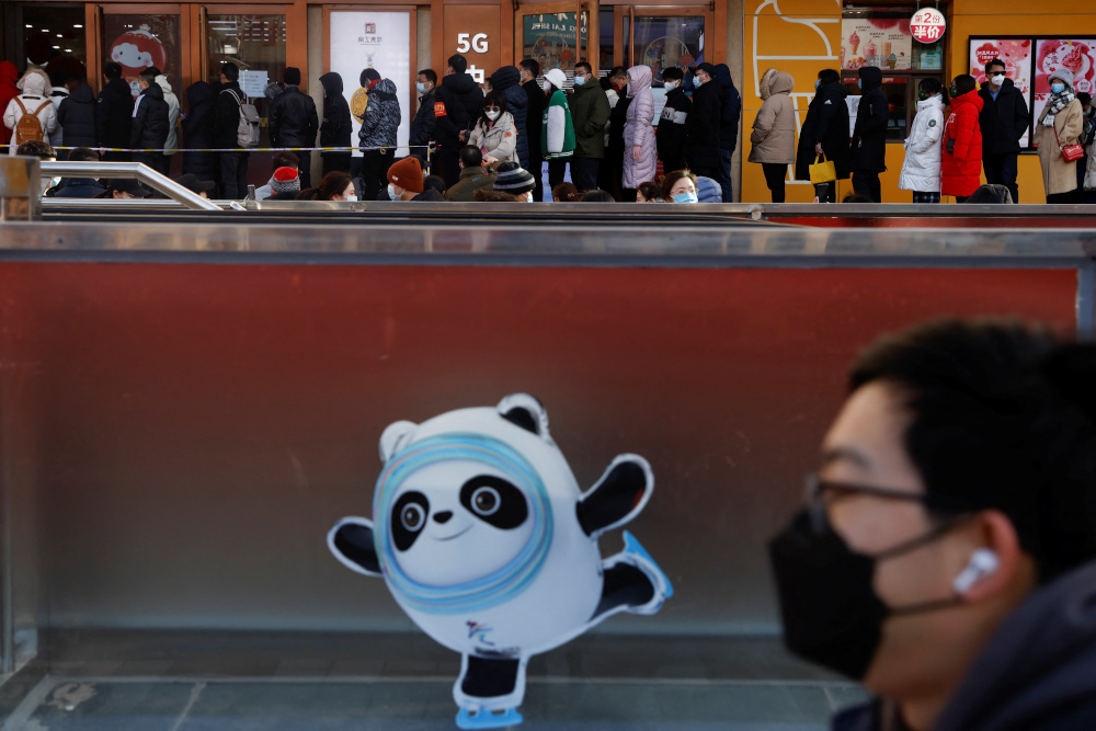 A man wearing a face mask walks past an image of Bing Dwen Dwen, the Beijing 2022 Winter Olympic Mascot, in front of people queueing to enter a flagship merchandise store for the Beijing 2022 Winter Olympics February 5, 2022. u00e2u20acu201d Reuters pic