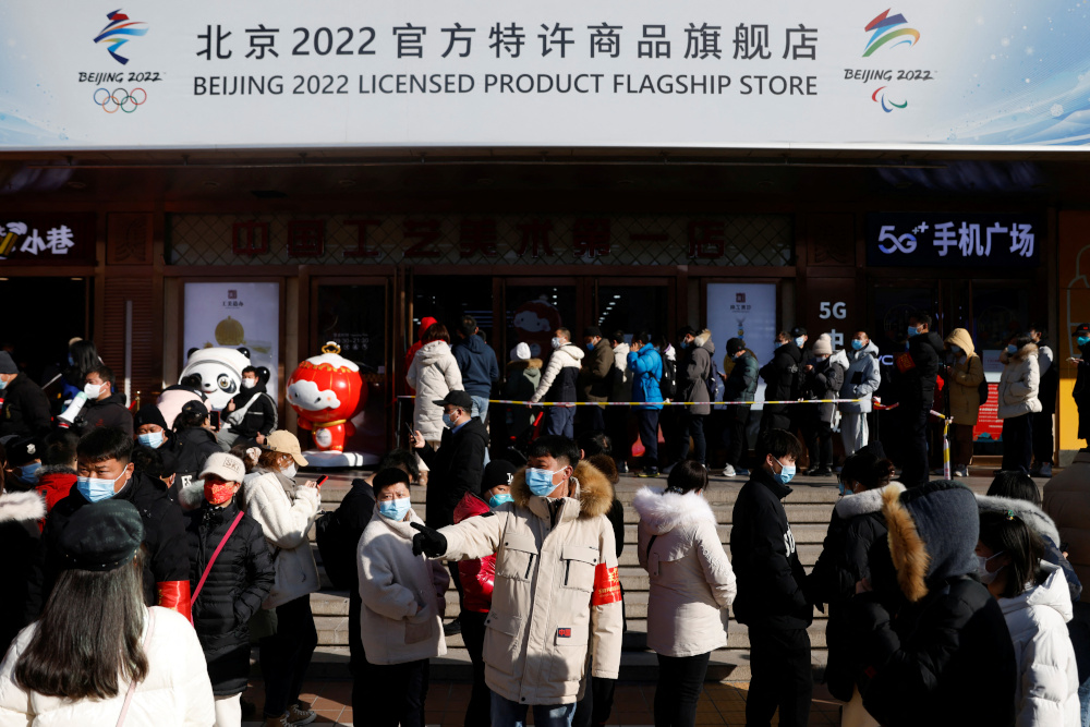 A staff member wearing a face mask organises the people queueing to enter a flagship merchandise store for the Beijing 2022 Winter Olympics at Wangfujing street in Beijing February 5, 2022. — Reuters pic