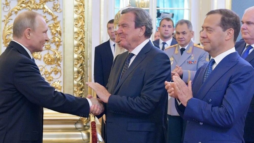 Schroeder shaking hands with Vladimir Putin in Moscow in 2018. u00e2u20acu201d SPUTNIK/AFP pic