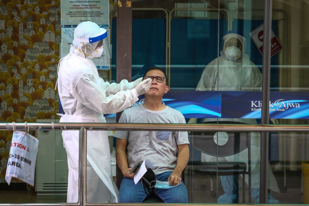 A health worker in protective suit collects swab samples from a motorist at a drive-through testing site for Covid-19 at Ajwa Clinic in Shah Alam February 9, 2022. u00e2u20acu201d Picture by Yusof Mat Isa