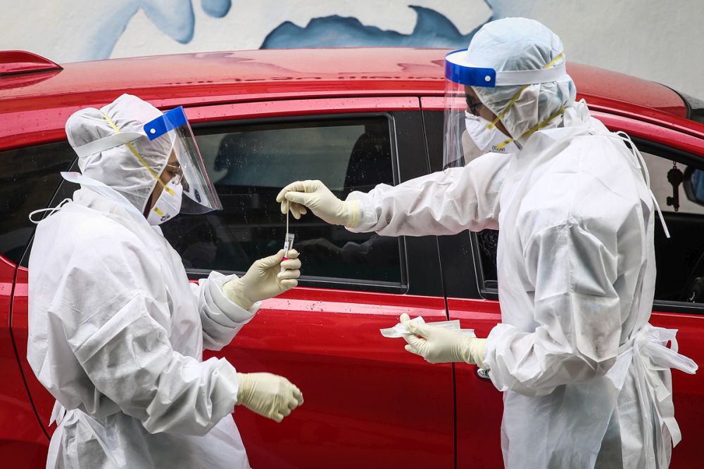 A health worker in protective suit collects swab samples from a motorist at a drive-through testing site for Covid-19 at Ajwa Clinic in Shah Alam February 9, 2022. u00e2u20acu201d Picture by Yusof Mat Isa
