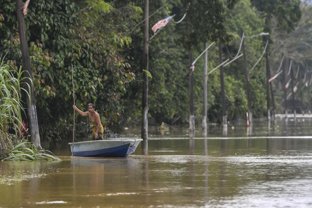 A resident rides a boat to check the water level at his home following continuous rain in Kampung Ayer Puteh in Kemaman, Terengganu, February 28, 2022. u00e2u20acu2022 Bernama pic 