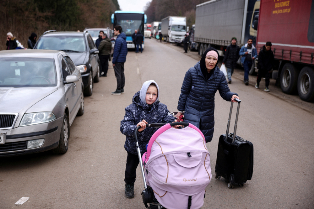 People fleeing Russiau00e2u20acu2122s military operation against Ukraine walk toward the Shehyni border crossing to Poland, next to vehicles lined up to cross the border, outside Mostyska, Ukraine, February 27, 2022. u00e2u20acu2022 Reuters pic 