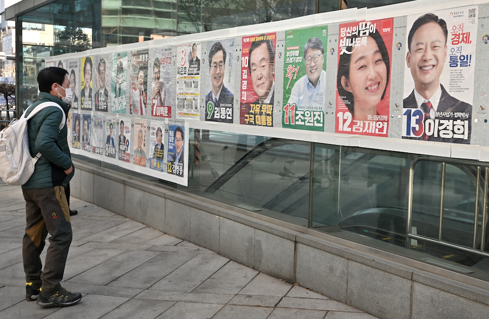 This picture taken on March 6, 2022 shows a man looking at posters of South Korea's presidential candidates (top row) in Seoul ahead of the March 9 presidential election. u00e2u20acu201d AFP pic