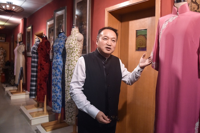 This photo taken on December 2, 2021 shows Zhou Zhuguang, the co-founder and designer of a traditional Chinese Qipao brand, showing his design at a Qipao studio in Shanghai. u00e2u20acu201d AFP pic
