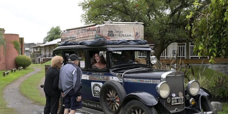 A couple chats with Argentinian Zapp family as they remain in their car, a 1928 Graham-Paige, as the family dog rests, near Gaualeguaychu, Entre Rios province. u00e2u20acu201d AFP pic