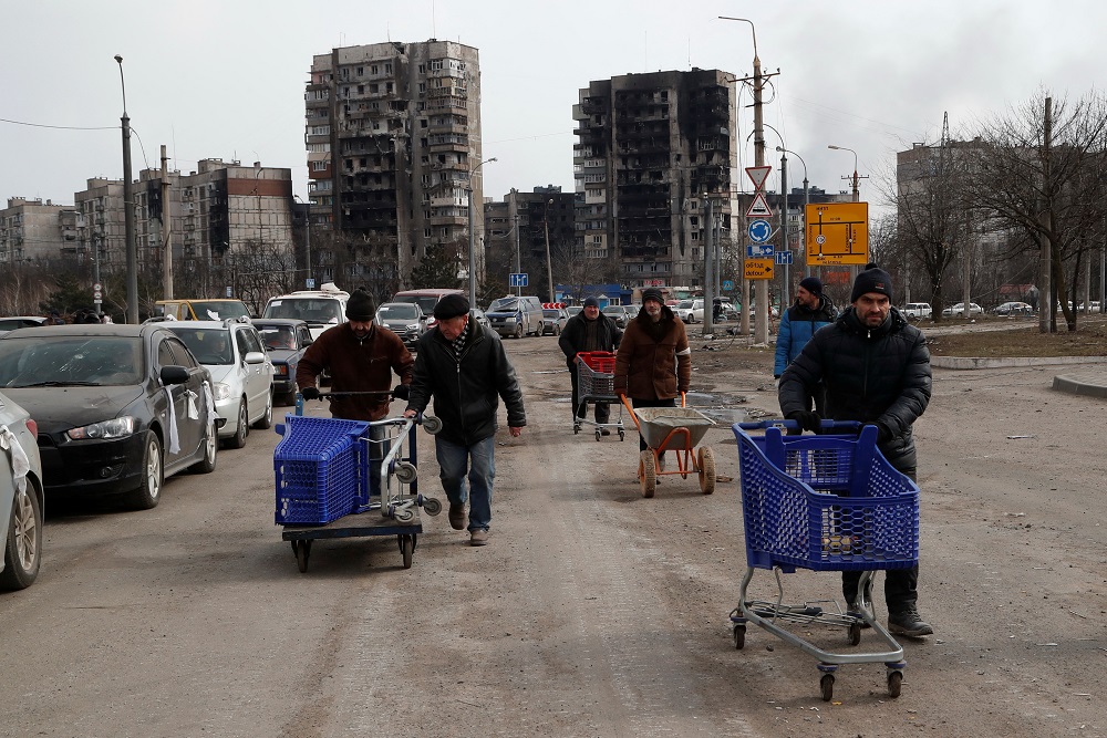 People walk near blocks of flats, which were destroyed during Ukraine-Russia conflict in the besieged southern port city of Mariupol, Ukraine March 17, 2022. — Reuters pic