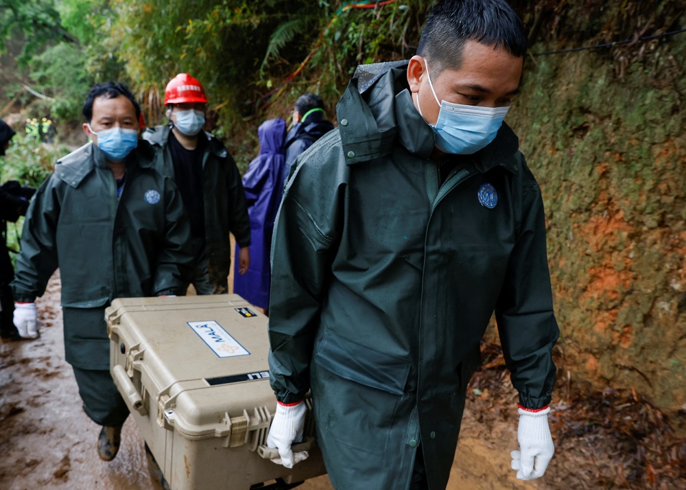 Workers carry a case at the site where a China Eastern Airlines Boeing 737-800 plane flying from Kunming to Guangzhou crashed, in Wuzhou, Guangxi Zhuang Autonomous Region, China March 24, 2022. u00e2u20acu201d Reuters pic