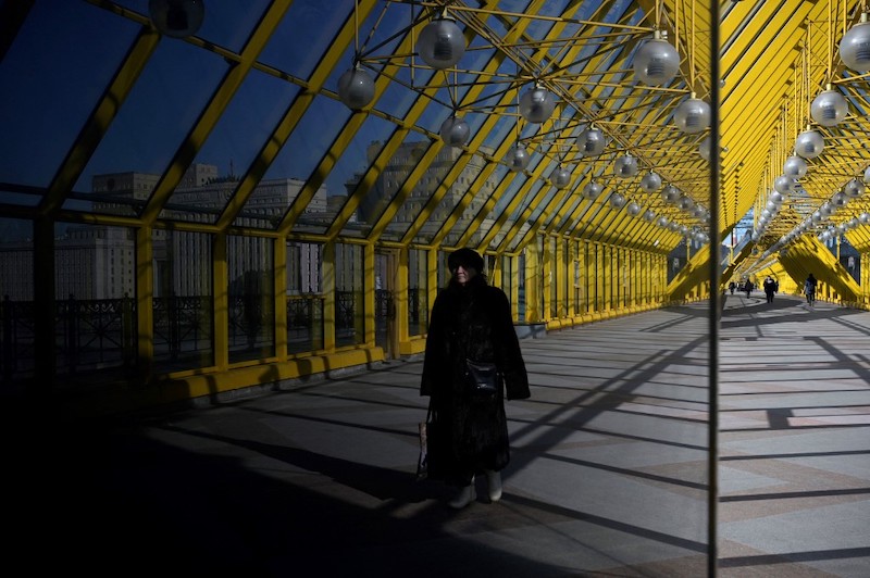 A woman walks along a pedestrian bridge across the Moskva river with the Russian Defence Ministry headquarters seen in the background in Moscow on March 1, 2022. u00e2u20acu201d AFP picnn