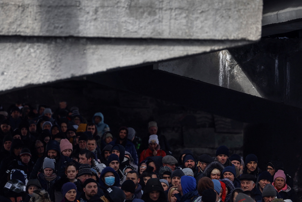 People wait below a destroyed bridge to cross a river as they flee from advancing Russian troops whose attack on Ukraine continues in the town of Irpin outside Kyiv, Ukraine, March 8, 2022. u00e2u20acu201d Reuters picn n