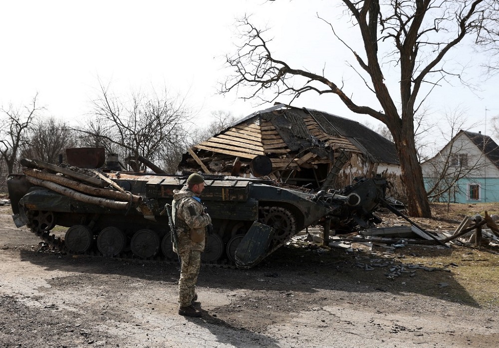 A Ukrainian soldier stands in front of a destroyed Russian armoured personnel carrier (APC) in a village on the frontline of the northern part of Kyiv region March 28, 2022. u00e2u20acu201d AFP pic