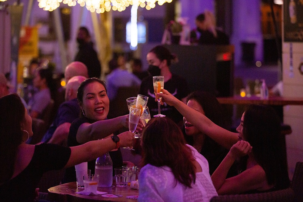 A group of customers at a bar in Clarke Quay raising their glasses for a toast. — TODAY pic