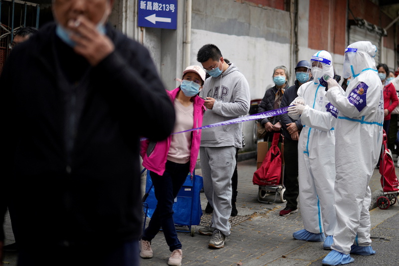 Police officers in protective suits set up cordon next to people lining up to buy food, following the coronavirus disease (Covid-19) outbreak in Shanghai, China March 30, 2021. u00e2u20acu201d Reuters picnn