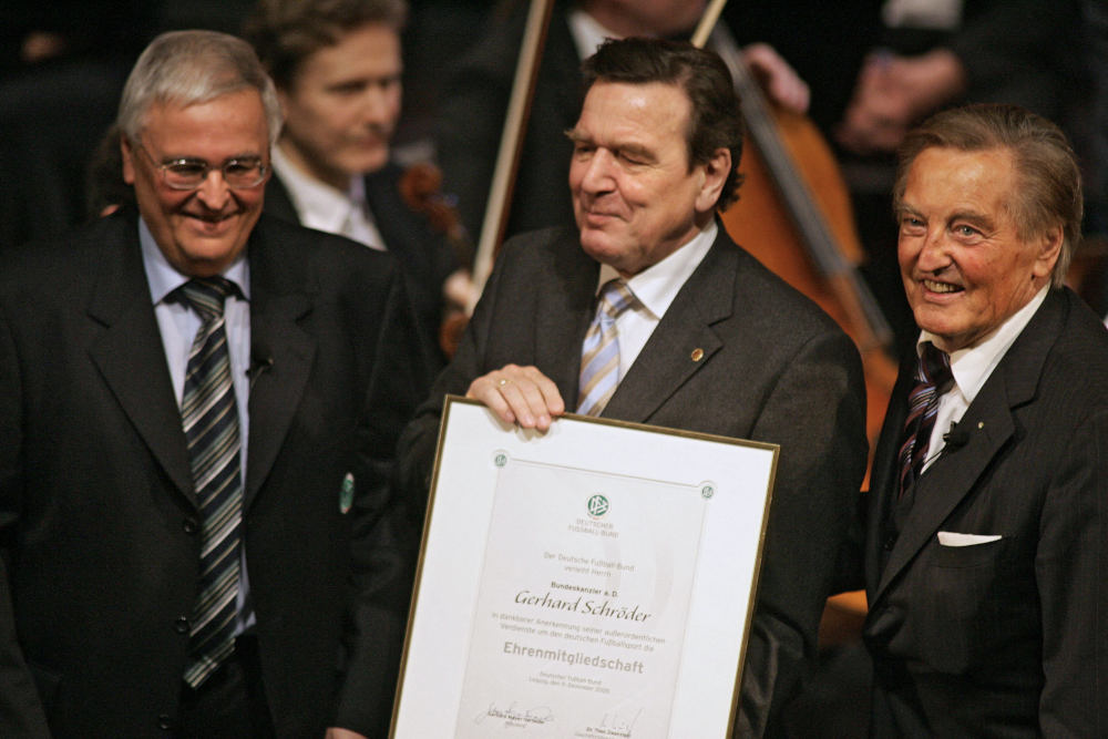 Former German Chancellor Gerhard Schroeder (centre) displays his certificate of DFB honorary membership as then DFB president Gerhard Mayer-Vorfelder (right) and its executive president Theo Zwanziger look on in Leipzig, Germany, December 9, 2005. u00e2u20acu201d AFP