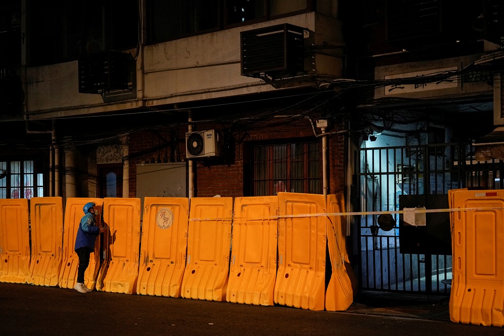A delivery worker waits to deliver food over barriers blocking a residential area, which have been built to separate buildings from a street, amid the Covid-19 pandemic, in Shanghai, China March 22, 2022. u00e2u20acu2022 Reuters pic