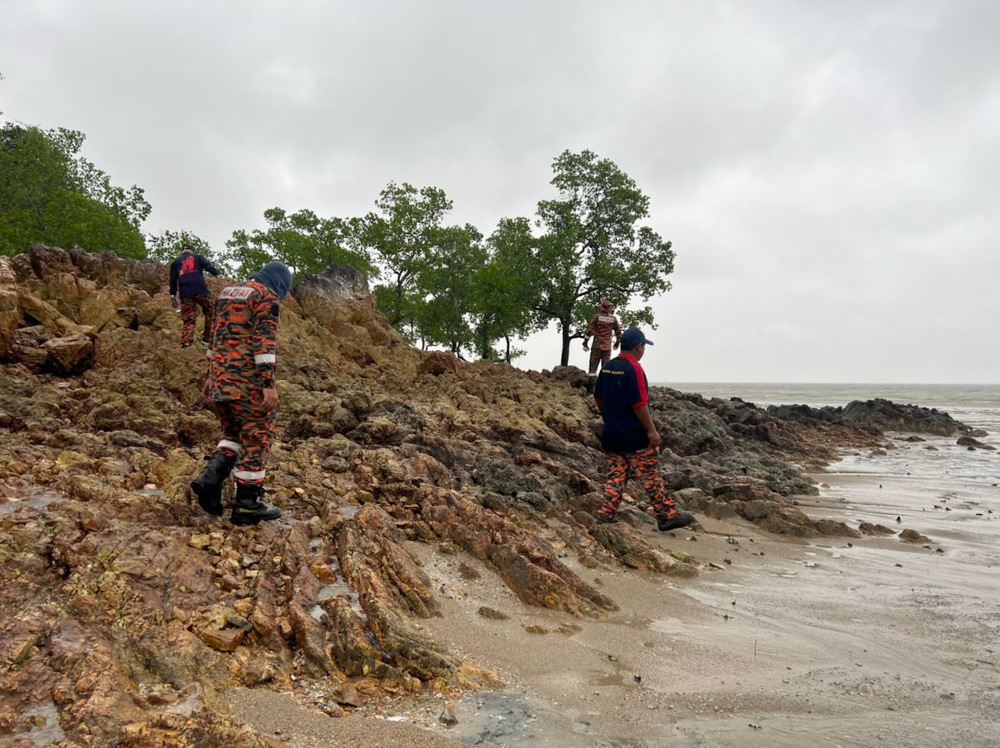 Bomba personnel conducting a ground search of around 300 metres around the the shoreline of Bukit Lasak while waiting for the tide to come in. u00e2u20acu201d Borneo Post pic