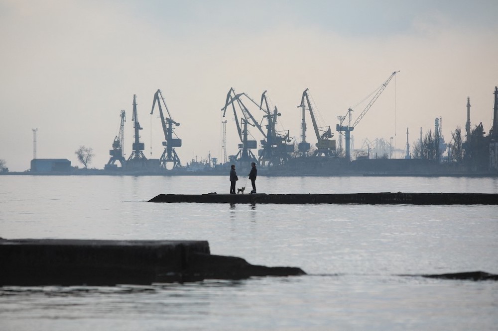 A couple walks a dog on a pier at a coast of the Sea of Azov in Ukraineu00e2u20acu2122s industrial port city of Mariupol on February 23, 2022. u00e2u20acu2022 AFP picnn
