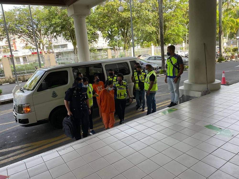 The two accused being escorted by police personnel upon their arrival at the courthouse today. u00e2u20acu201d Borneo Post Online pic