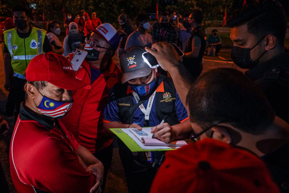 Enforcement personnel from the Health Ministry issue a compound to the organiser at Pakatan Harapan’s Ceramah Mega, main operations room for DUN N49 Kota Iskandar, Skudai, March 1, 2022. ― Picture by Hari Anggara 