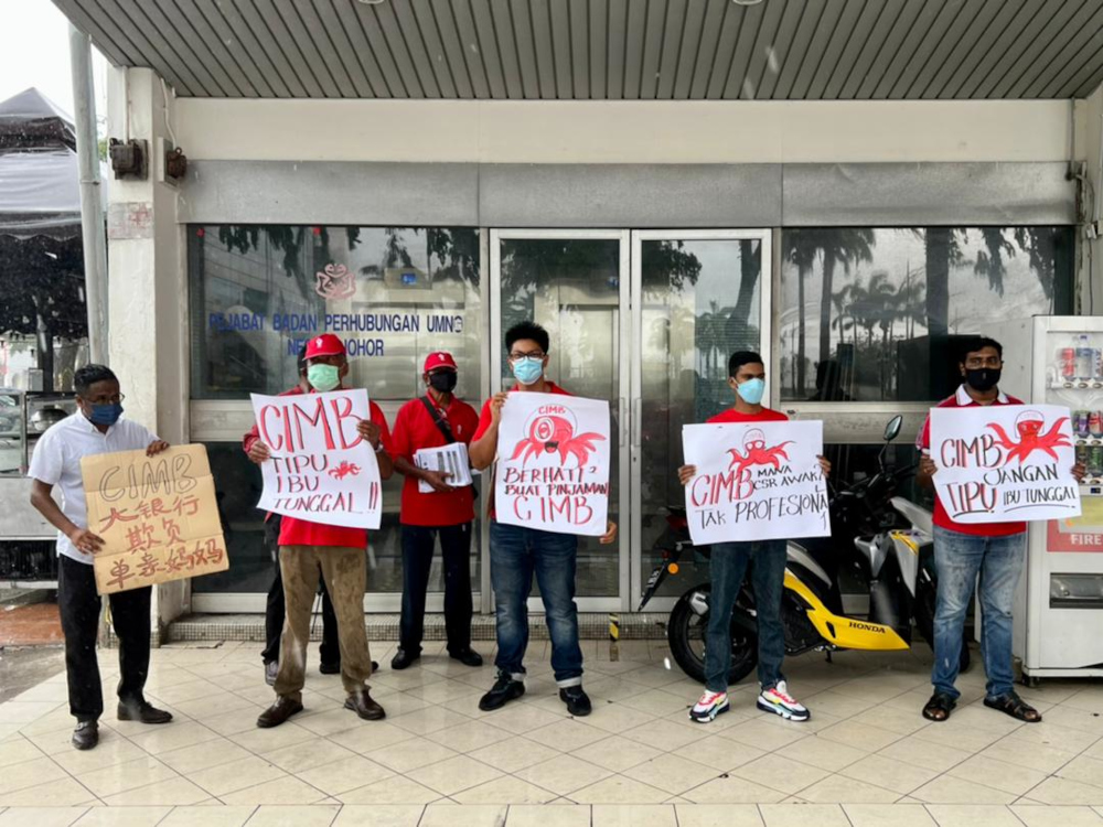 PSM activist Poopathy Subramaniam (left) and the partyu00e2u20acu2122s activists with placards condemning CIMBu00e2u20acu2122s alleged actions at the Johor Baru CIMB bank branch along Jalan Segget in Johor Baru, March 31, 2022. u00e2u20acu201d Picture by Ben Tan