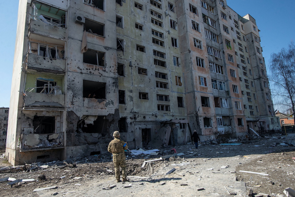A Ukrainian service member stands in a front of a residential building damaged by a shelling, as Russiau00e2u20acu2122s attack on Ukraine continues, in the town of Okhtyrka, in the Sumy region, Ukraine March 24, 2022. u00e2u20acu201d Reutersnn
