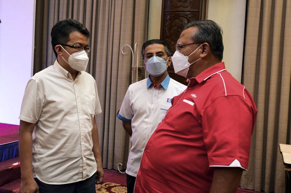 Johor Pakatan chief Aminolhuda Hassan (right) speaks to Syed Ibrahim Syed Noh (centre) and Liew Chin Tong at the Pakatan Harapan command centre in Senai March 12, 2022. u00e2u20acu201d Bernama pic