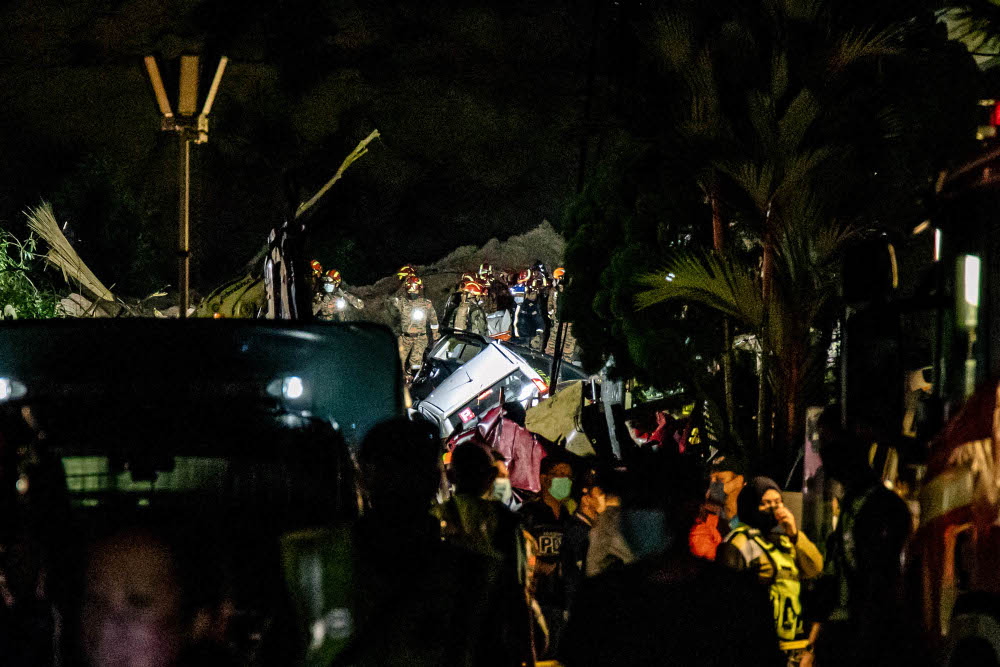 Search and rescue personnel lift one of the bodies recovered from the landslide at Taman Bukit Permai 2 Ampang, March 10, 2022. — Picture by Firdaus Latif