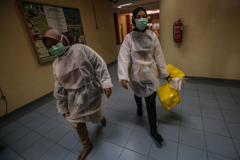 Personnel from the Institute for Medical Research transporting a test sample which was later found to be positive. u00e2u20acu201d Picture by Hari Anggara