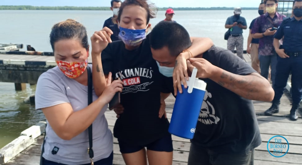 Dynasty Chang (centre) being helped by her husband and a relative as they left the Muara Tebas Wharf March 14, 2022. u00e2u20acu201d Picture by Jacqueline David/Borneo Post