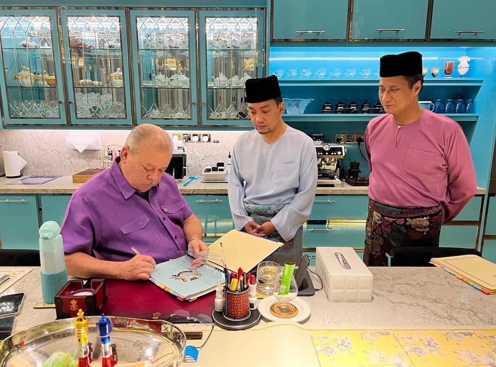 Johor Ruler Sultan Ibrahim Sultan Iskandar signing the official document consenting to the swearing-in of the stateu00e2u20acu2122s executive councillors at the Balai Mengadap of the Istana Bukit Serene this Saturday. u00e2u20acu201d Picture via Facebook