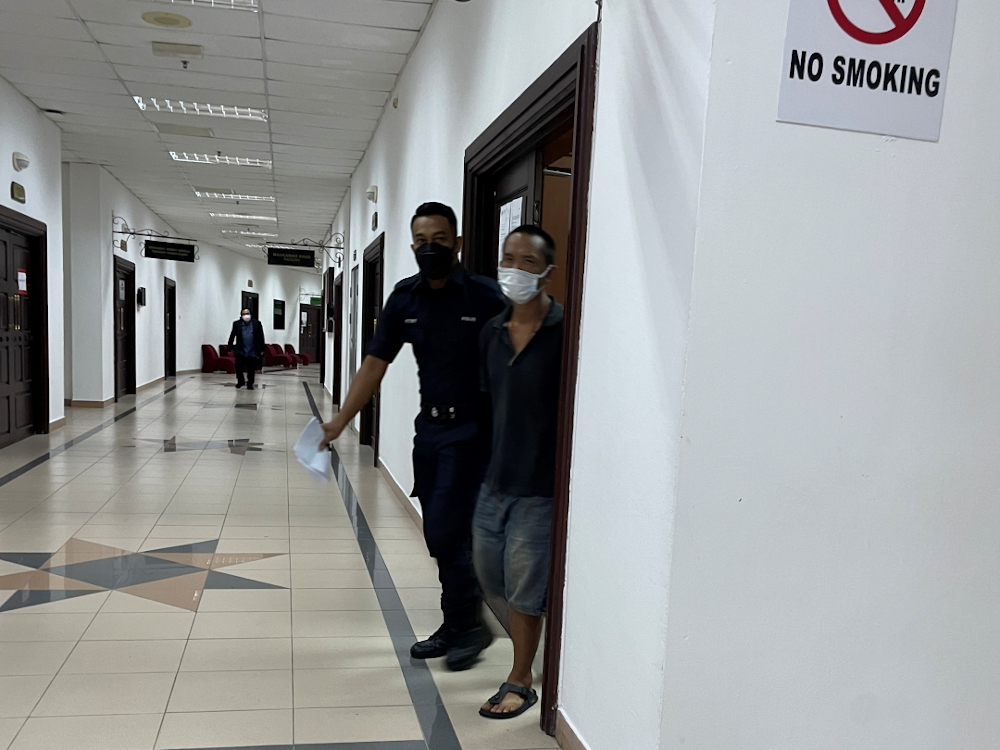 The accused (right) being escorted out of the courtroom. u00e2u20acu201d Borneo Post pic