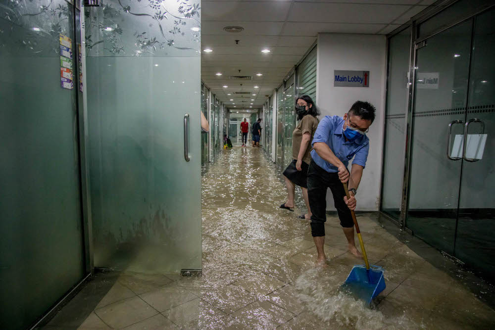 Office workers remove rainwater in their office due to the heavy rain in Kuala Lumpur, March 7, 2022. — Picture by Firdaus Latif